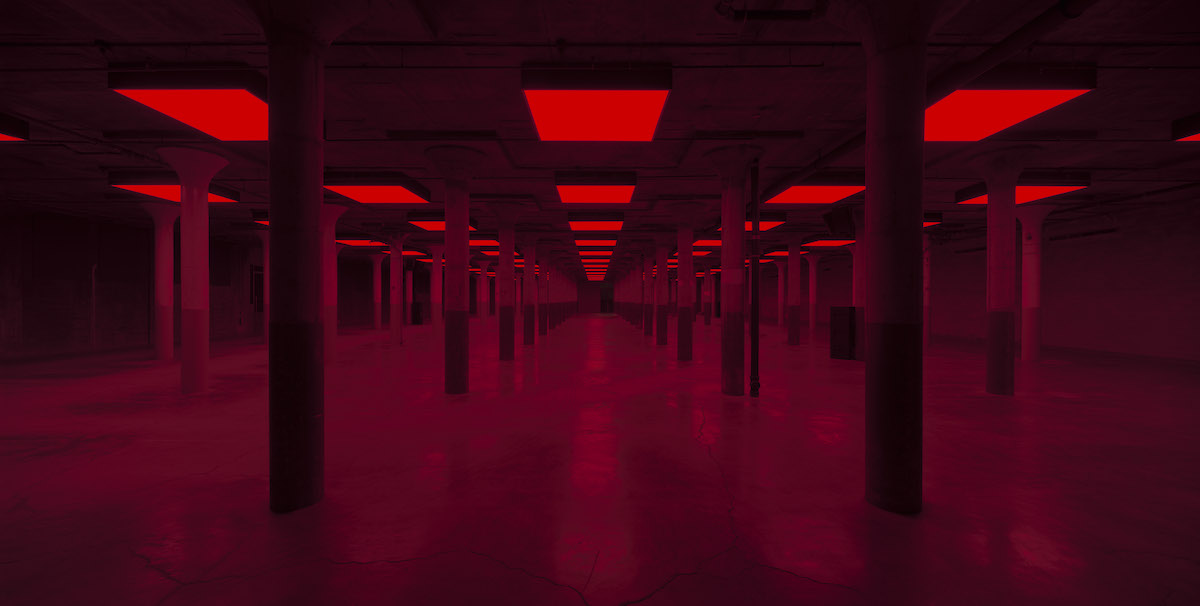 An empty columned space lit vibrant red.