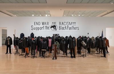 A group of headless mannequins beneath a sign that reads 'END WAR AND RACISM!!! Support the Black Panthers.'